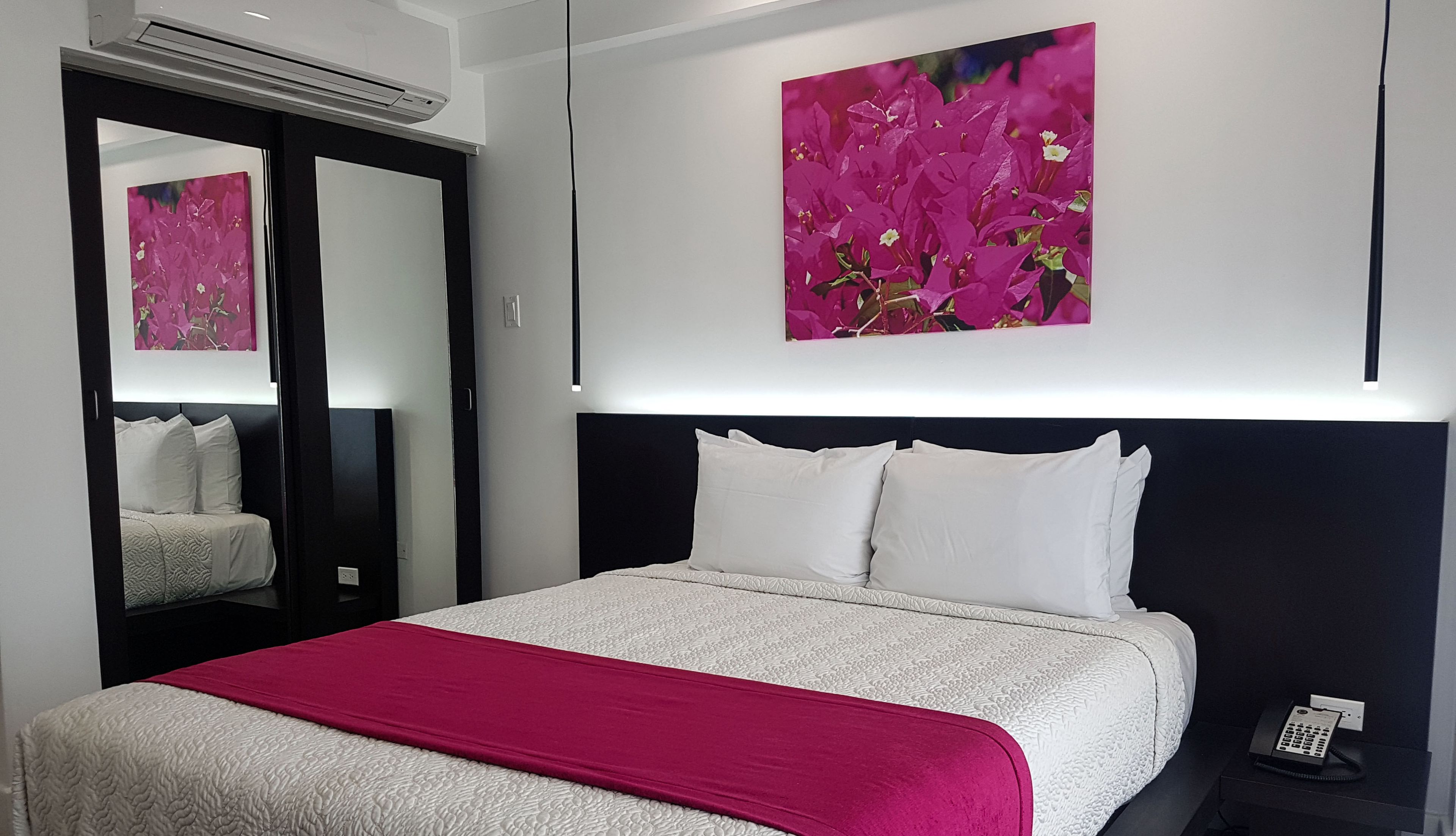 Une chambre d’hôtel avec un lit, une table de chevet, un téléphone et un tableau au mur.