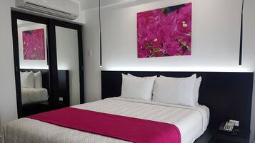 Une chambre d’hôtel avec un lit, une table de chevet, un téléphone et un tableau au mur.