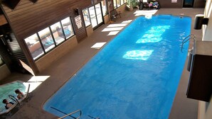 An indoor swimming pool with clear water, a diving board, and a lifeguard chair. - Mountainside 2 Bed 2 Bath (Frisco)