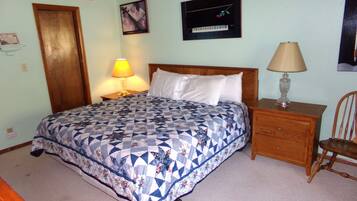 A bedroom with a bed, a nightstand, a chair, and a wall-mounted lamp.