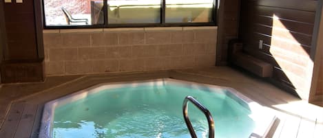 Ein Whirlpool mit Holzterrasse und Blick durch ein Fenster.