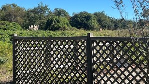 A wooden lattice fence with a view of dense greenery and trees in the background. - Toadally Relaxin' 2 Bedroom Home by RedAwning (Supply)