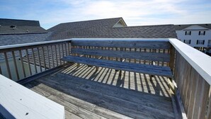 A wooden deck with a bench, surrounded by a railing, overlooking a residential area with houses. - Toadally Relaxin' 2 Bedroom Home by RedAwning (Supply)