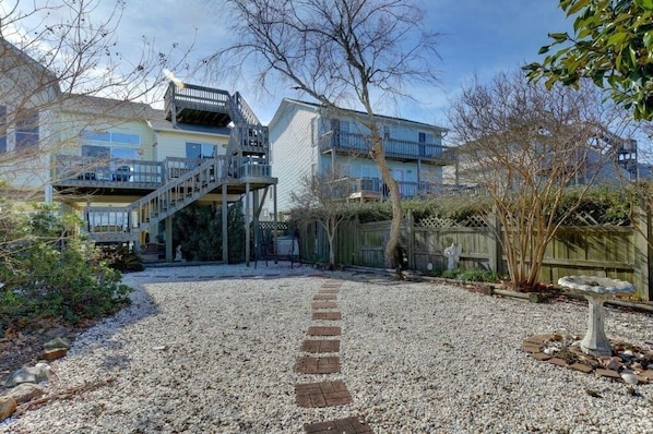A residential building with a gravel driveway, wooden fence, and a birdbath.