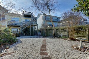 Un edificio residencial con camino de entrada de grava, cerca de madera y un bebedero para pájaros.