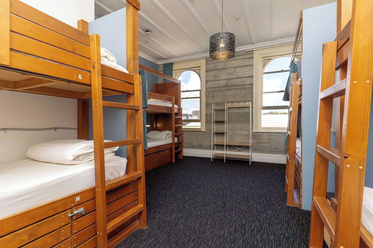 A bunk room with wooden bunk beds, a small desk, and a window with a view.