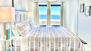 A bedroom with a bed, a ceiling fan, and a view of the ocean.