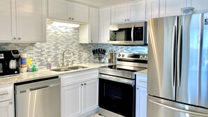 A modern kitchen with white cabinets, stainless steel appliances, a microwave, and a dishwasher.