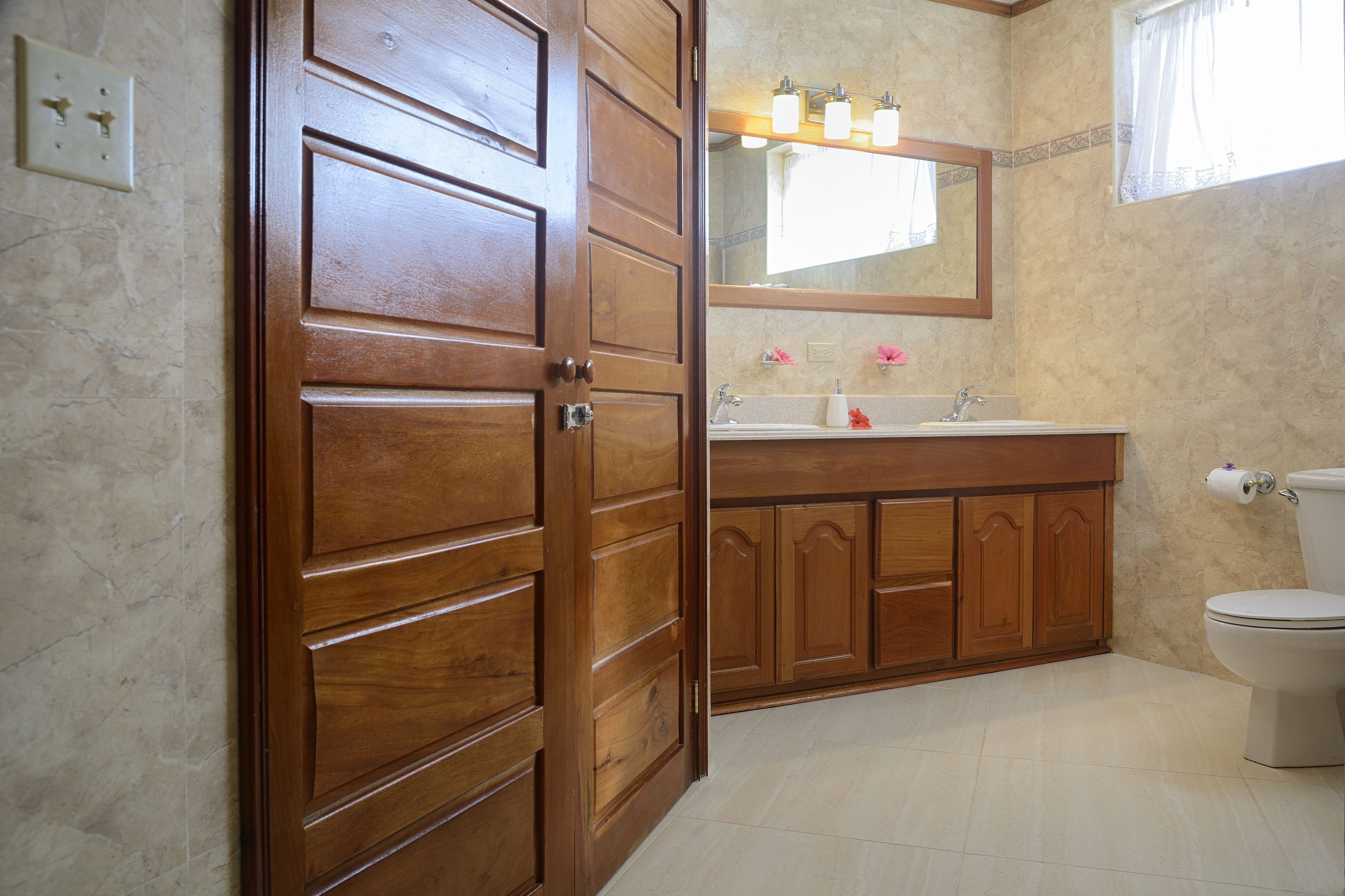 A bathroom with a wooden vanity, a toilet, and a mirror above the sink.