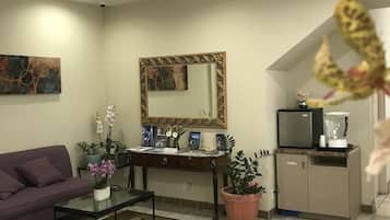 Una sala de estar con un sofá morado, una mesa de centro, un televisor, un mueble y un espejo.