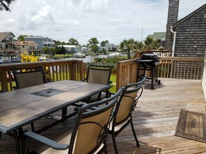 En udendørs terrasse med et bord og stole, med udsigt over vand og en lysthavn.