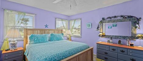 Un dormitorio con cama, cómoda, ventilador de techo y ventana con persianas.