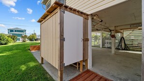 Uma construção de madeira com porta, chão de concreto e gramado.