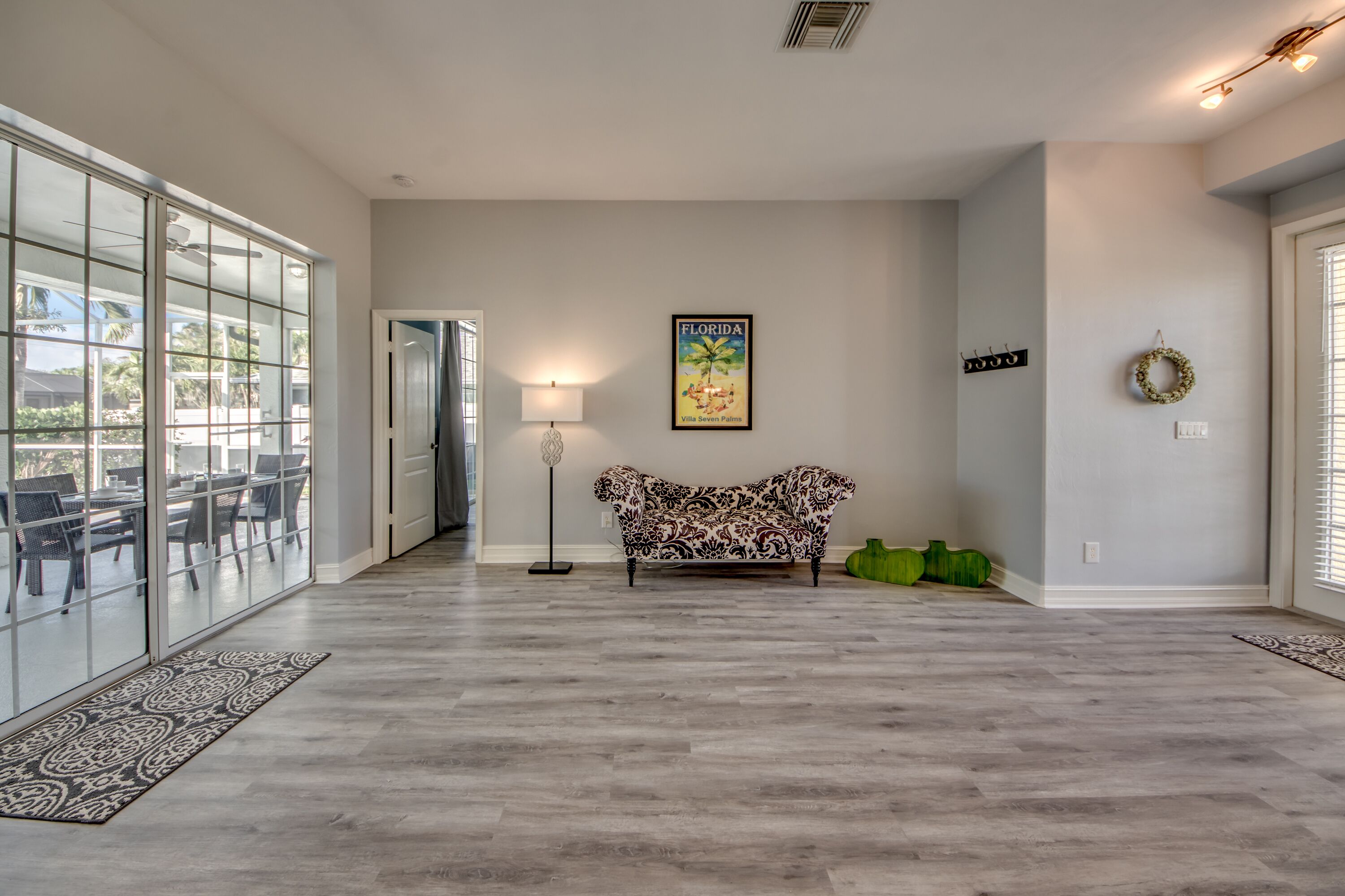Amplia sala de estar con un sofá estampado, una lámpara de pie y una decoración de pared temática de Florida.