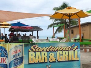 Een strandbar en grill genaamd 'Santanna's' met terras en parasols.