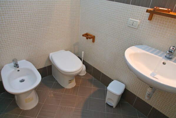 A bathroom with a bidet, toilet, and sink.
