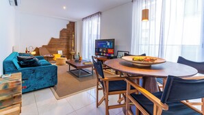 Ein modernes Wohnzimmer mit einem blauen Sofa, einem Holzesstisch und einem Fernseher.