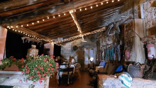 A rustic stone interior with a wooden ceiling, string lights, and a stone wall with various items. - Stone Farmhouse in Chianti Hill between Florence, Siena private veranda and lake (Radda in Chianti)