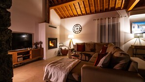 A cozy living room with a fireplace, a television, and a comfortable sofa.