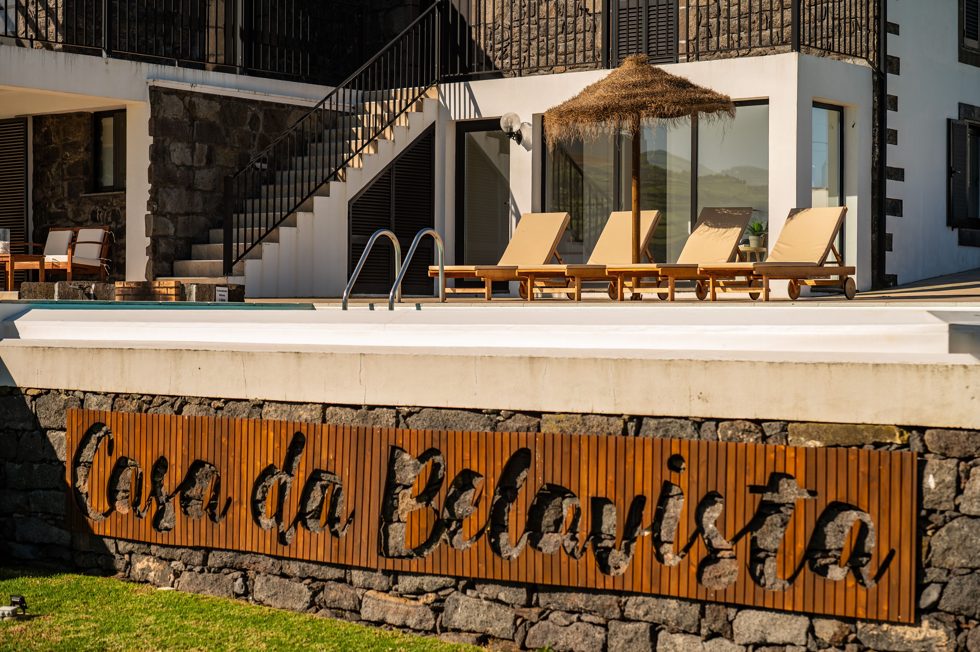 Ett modernt semesterhotell med en pool, solstolar och en skylt med texten ”Casa da Bela Vista”.