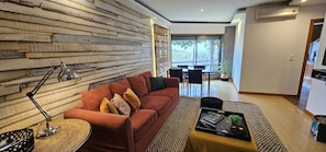 A modern living room with a red sofa, a coffee table, a lamp, and a view to the outside.