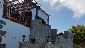 Un bâtiment en pierre doté d’un balcon, de murs en pierre et d’une pergola.