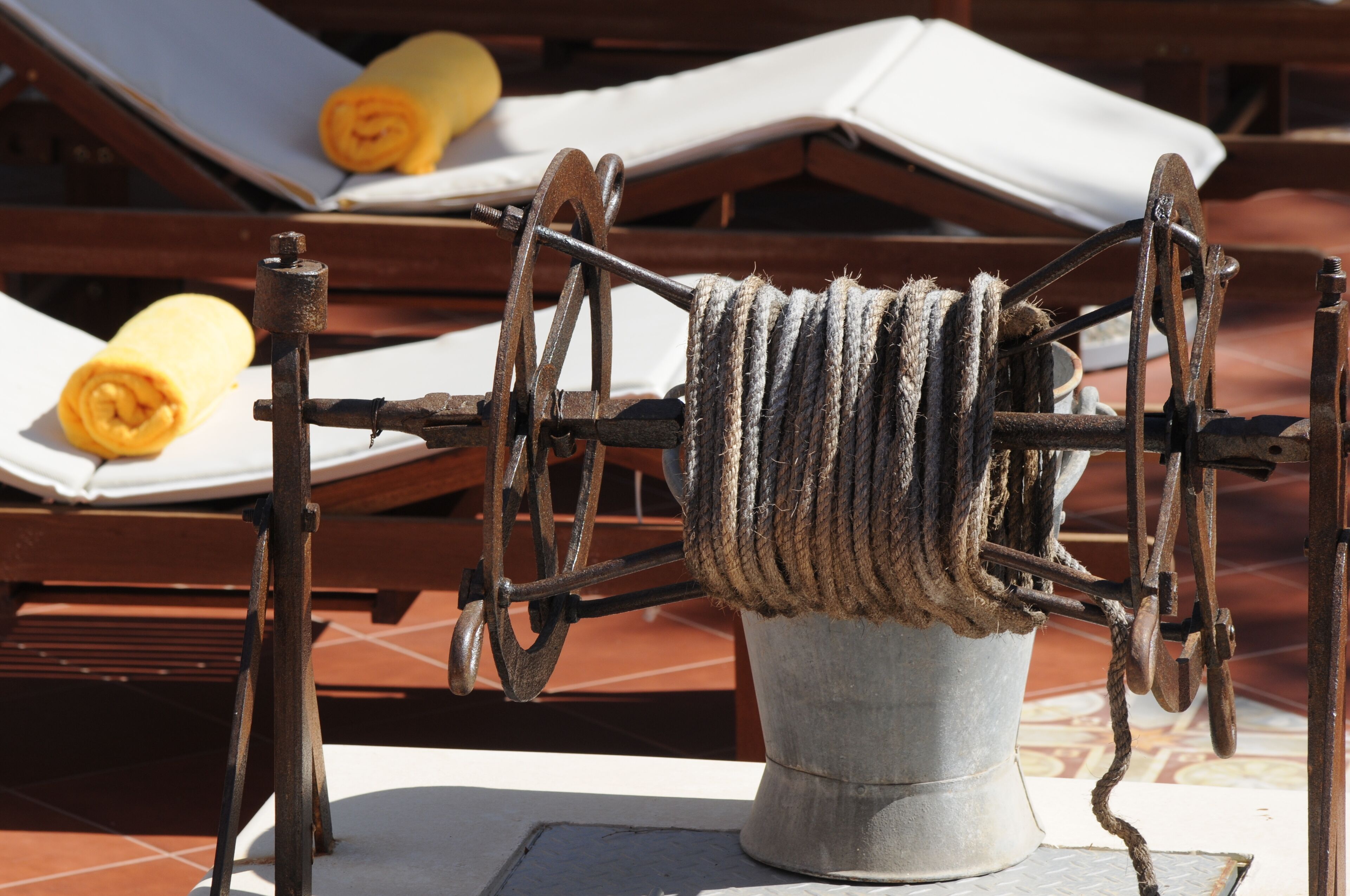 A rustic outdoor setting with a mechanical device, possibly for drying or processing materials, surrounded by wooden furniture and a tiled floor.