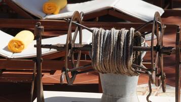 A rustic outdoor setting with a mechanical device, possibly for drying or processing materials, surrounded by wooden furniture and a tiled floor.