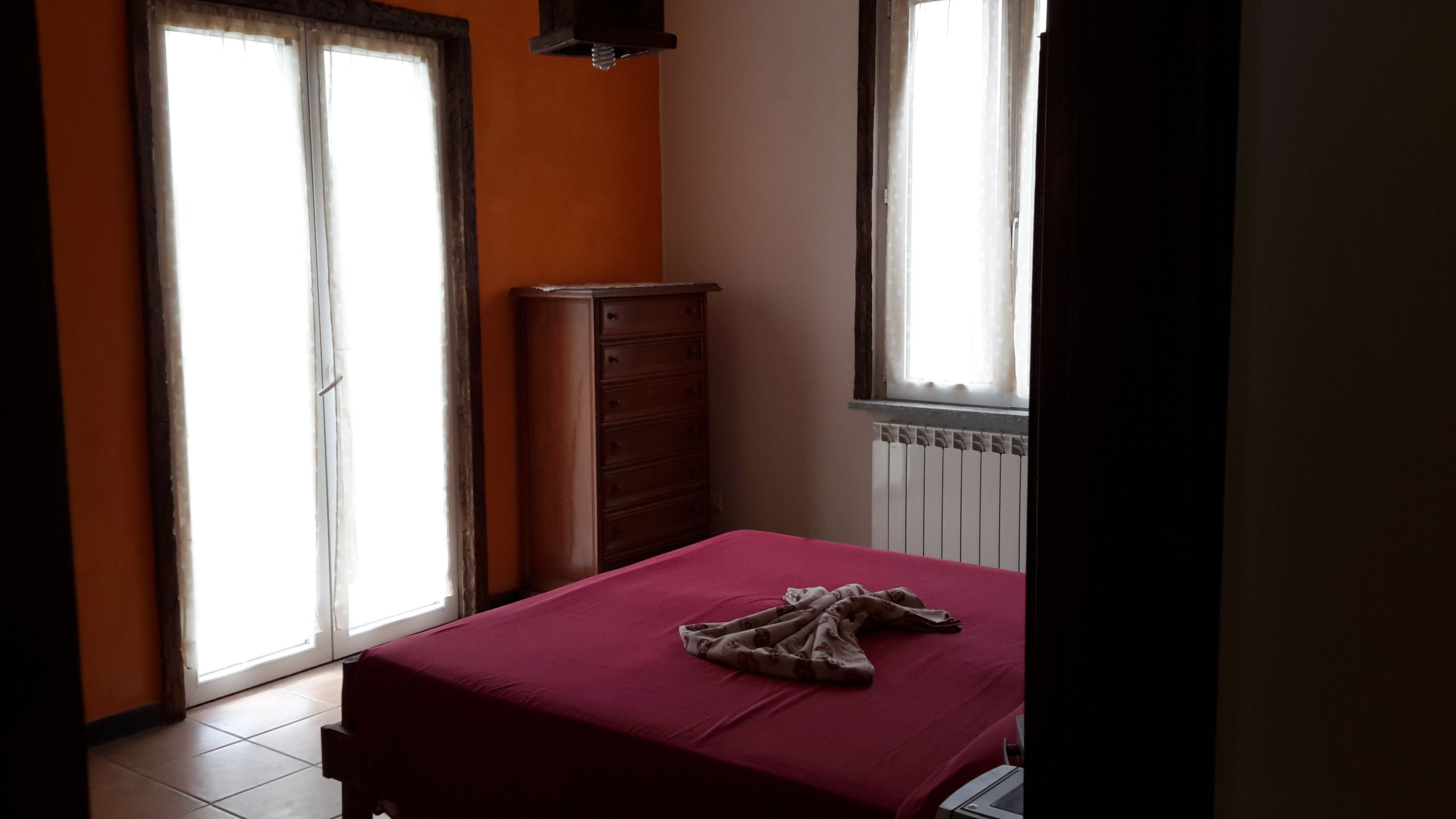 A bedroom with a bed, a dresser, and a window with curtains.