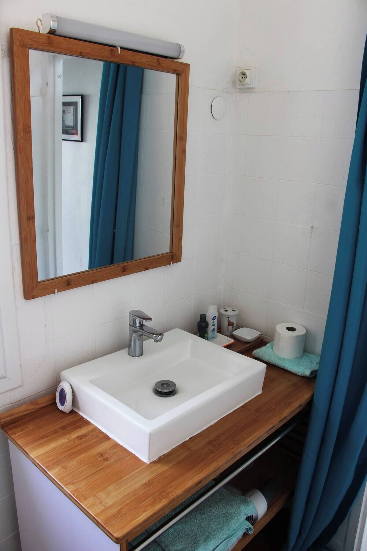 A bathroom with a wooden vanity, white sink, and a mirror with a wooden frame.