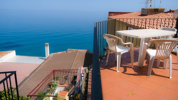 A terrace with a table and chairs, overlooking a body of water. - Terrazza Giudecca (Cefalù)