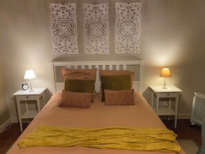 A bedroom with a bed, two nightstands, a lamp, a clock, and decorative wall panels. - Ribeira dos Caldeirões - Natural Park (Nordeste)