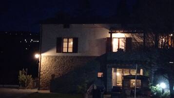 Une maison en pierre à deux étages, dotée d’une entrée bien éclairée et d’une fenêtre visible à l’étage supérieur.