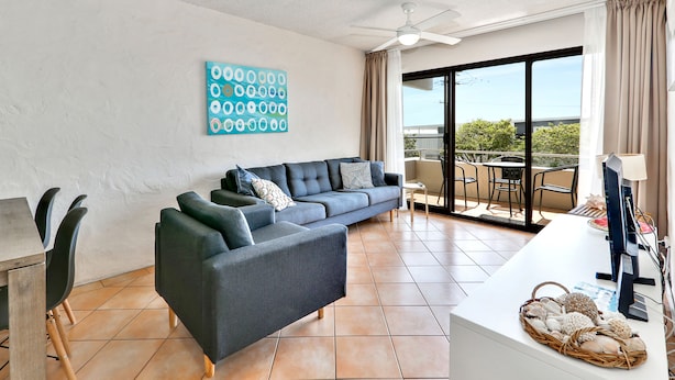 A modern living room with a sectional sofa, a dining table, and a TV. - Warroo (Alexandra Headland)