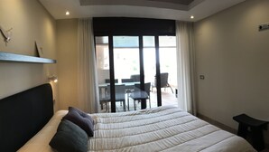 Une chambre d’hôtel avec un grand lit, une petite table et une vue sur l’espace extérieur aménagé avec des sièges.