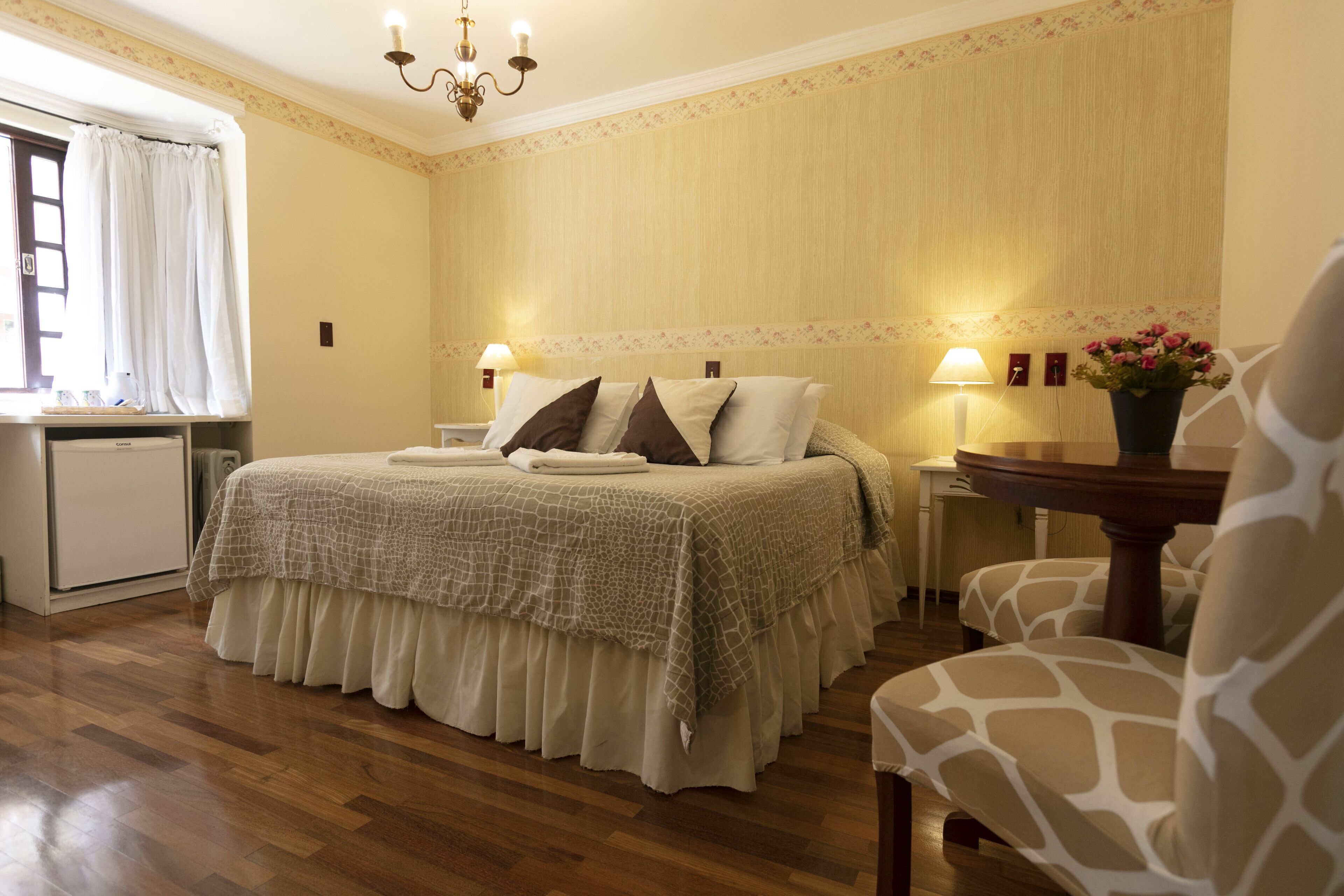 A bedroom with a bed, bedside tables, a chair, and a window with curtains.