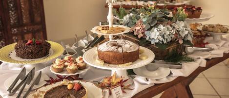 A buffet table with various desserts and a floral arrangement.