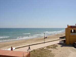 A beach view with a paved walkway, a restaurant named 'Don Catalina', and a clear sky.