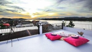 A balcony with a view of a lake and distant hills, featuring a tripod and two pink cushions. - The Royal Chiangkhan Boutique Hotel (Chiang Khan)