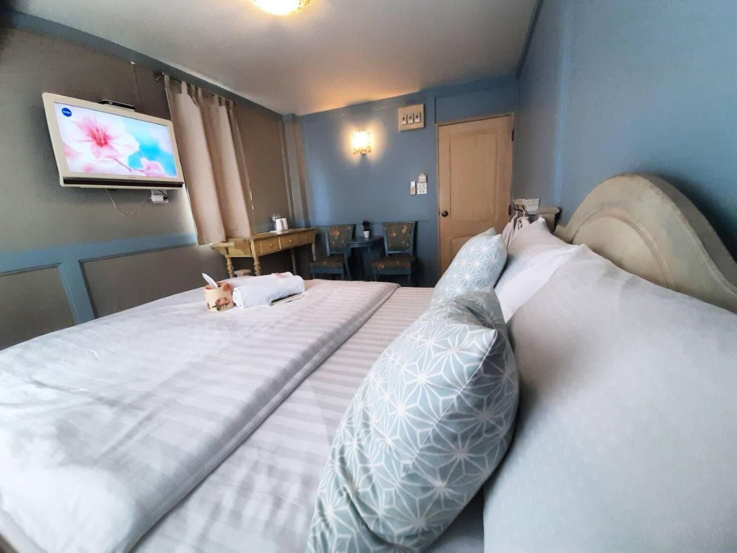 A hotel room with a bed, a desk, a chair, a television, and a door.