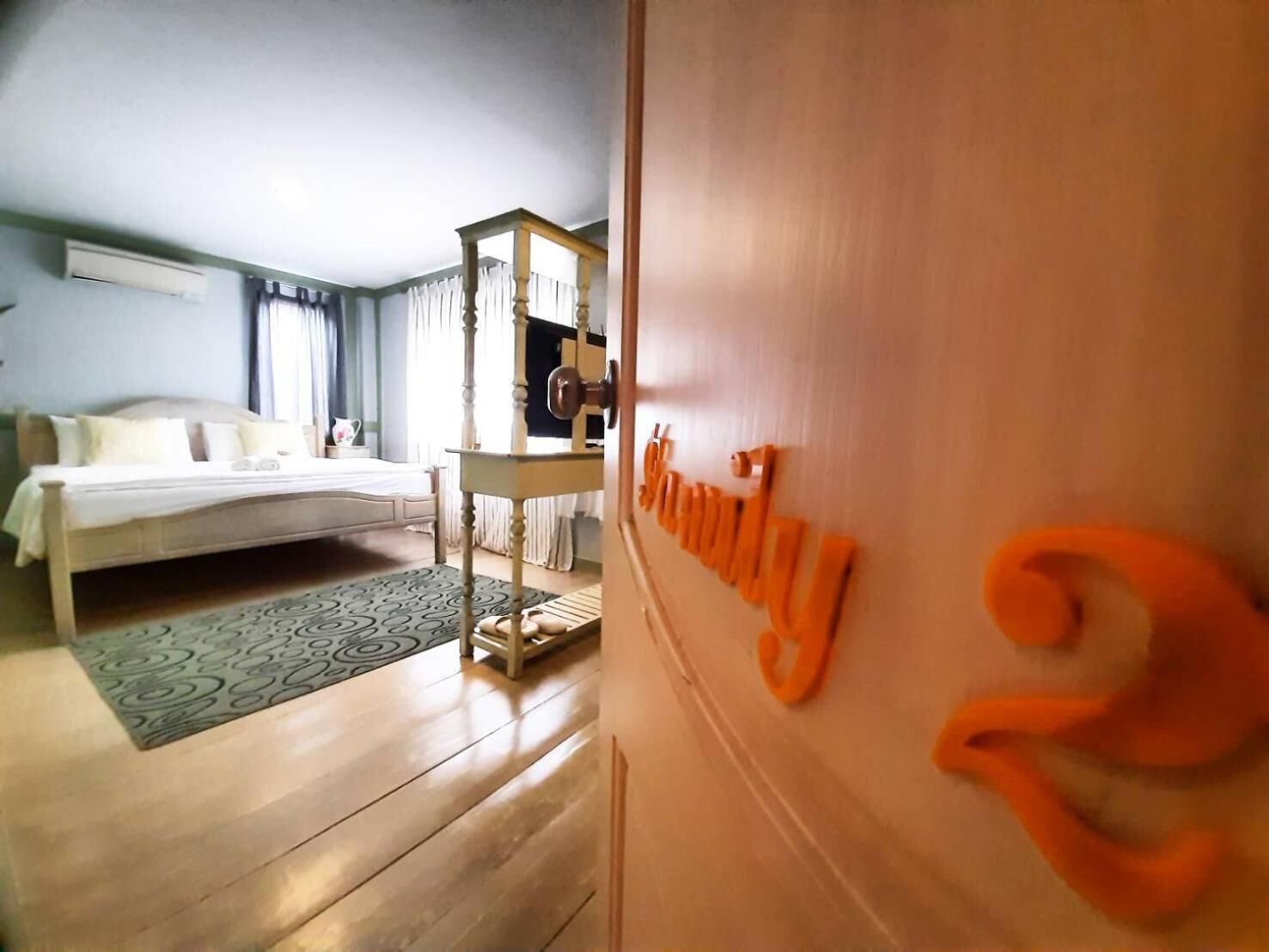 A hotel room with a bed, a wooden dresser, and a desk with a chair.