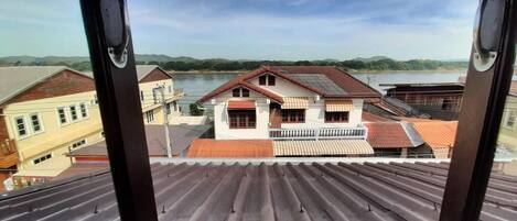 A view from a window overlooking a river and buildings with a corrugated metal roof.