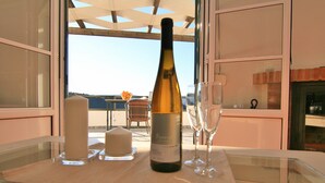 Une bouteille de vin sur une table, avec une bougie et un verre, le tout placé devant un balcon offrant une vue panoramique.