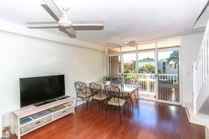 Relax in this living area with a flat-screen TV, dining table, and sliding glass door leading to a balcony.