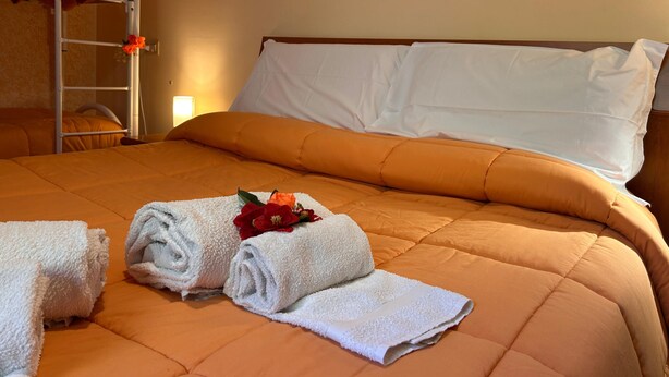 Een hotelkamer met een bed, een stapelbed en een nachtkastje met een lamp.