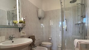 Een moderne badkamer met een douche met glazen wand, een wastafel, een bidet en een toilet.