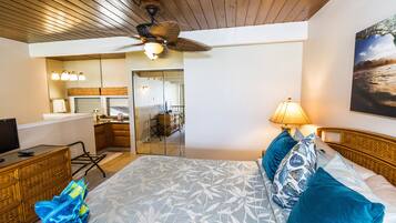 Quarto com cama, escrivaninha, cadeira, ventilador de teto, luminária e um quadro na parede.
