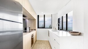 A modern kitchen with a large window, a built-in oven, and a sleek refrigerator. - Breeze Apartment 801 (Mooloolaba)