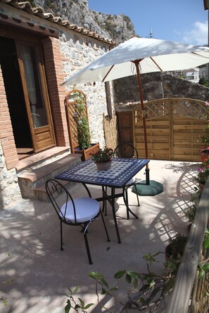 An outdoor patio with a table and chairs, a potted plant, and a wooden fence.