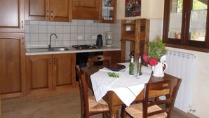 Una cocina con armarios de madera, salpicadero de azulejos, estufa y una mesa de comedor con sillas.